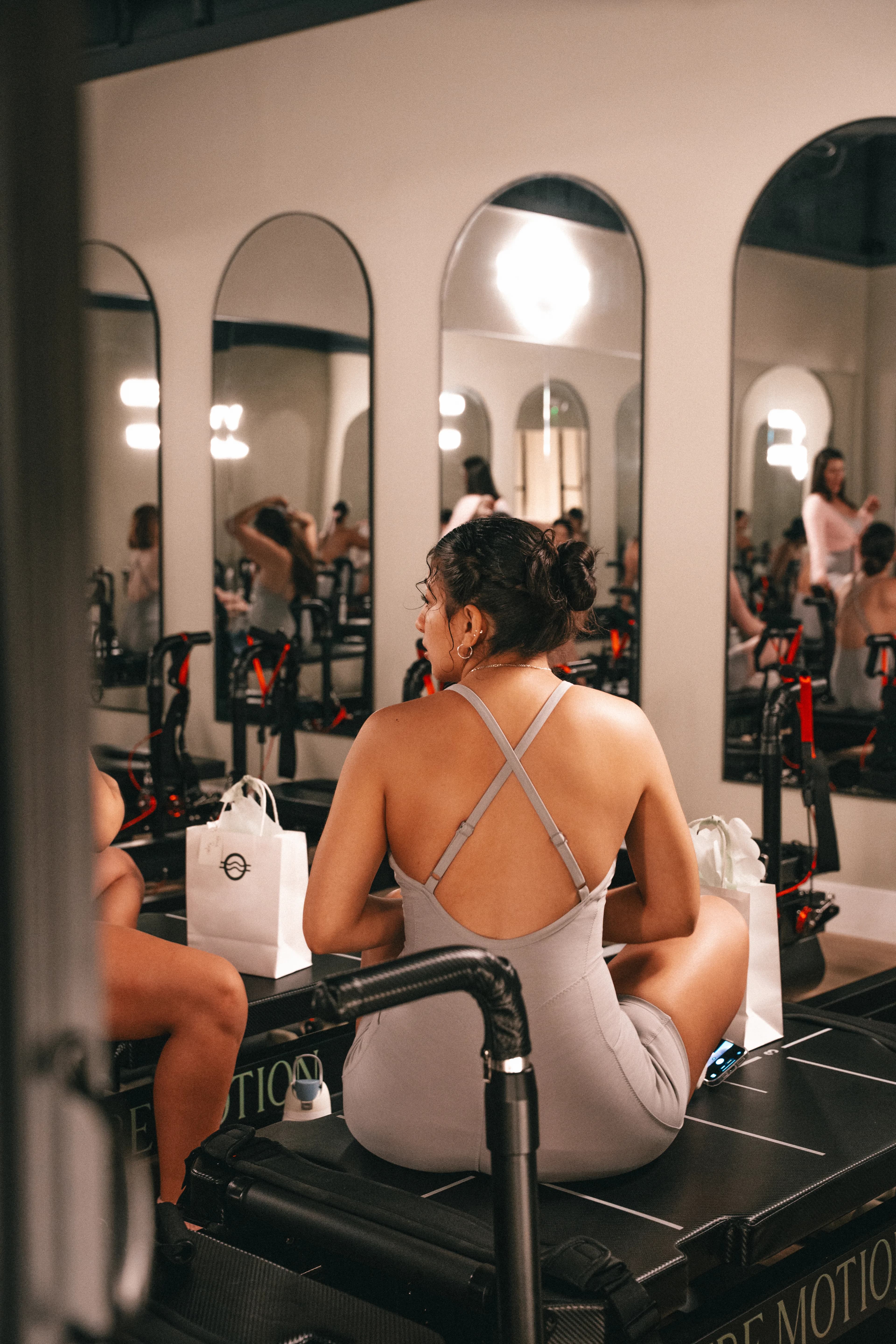 A guest sits at the reformer facing the studio mirrors at Pure Motion.