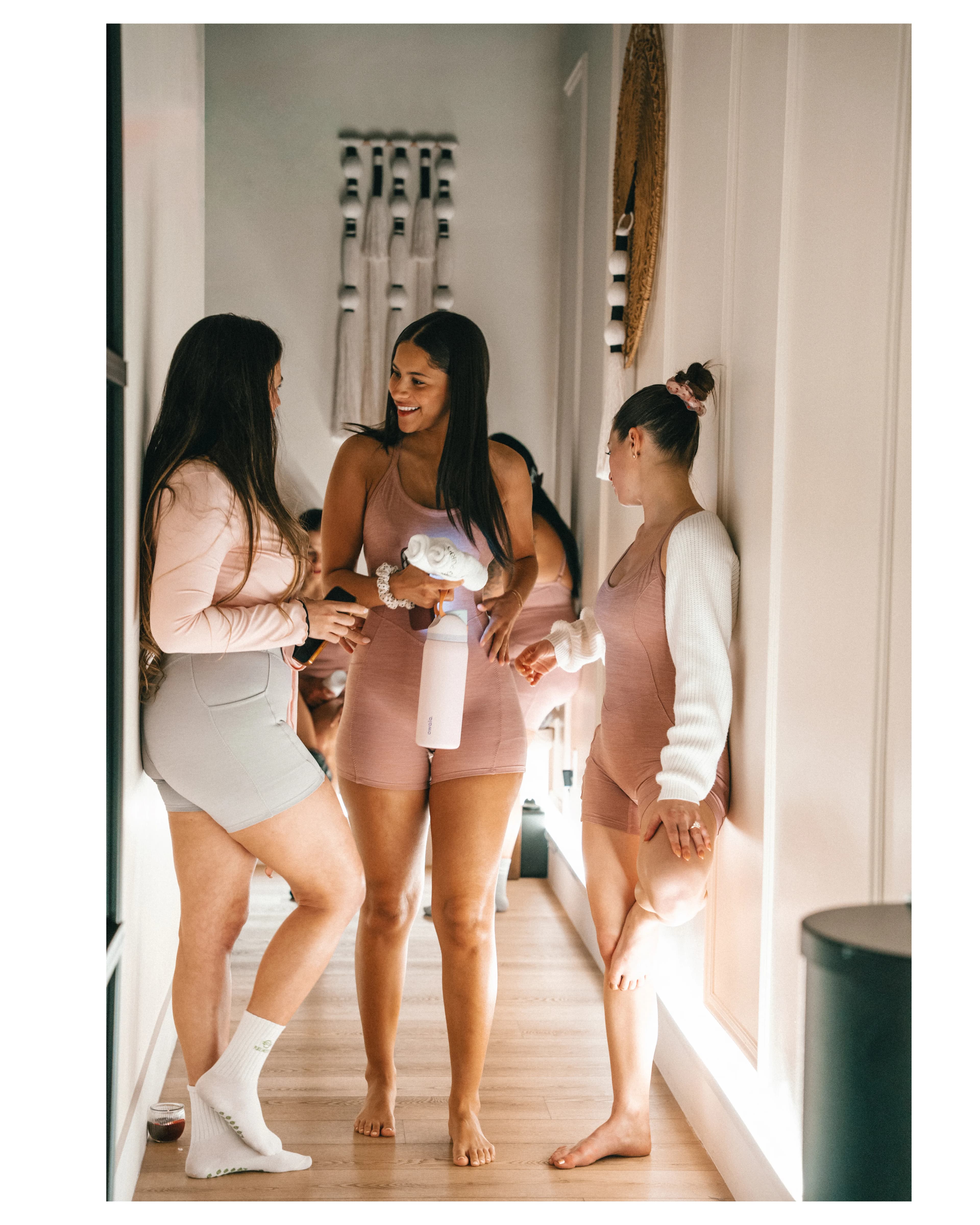 Three guests in loungewear share drinks in the bright studio at Pure Motion.