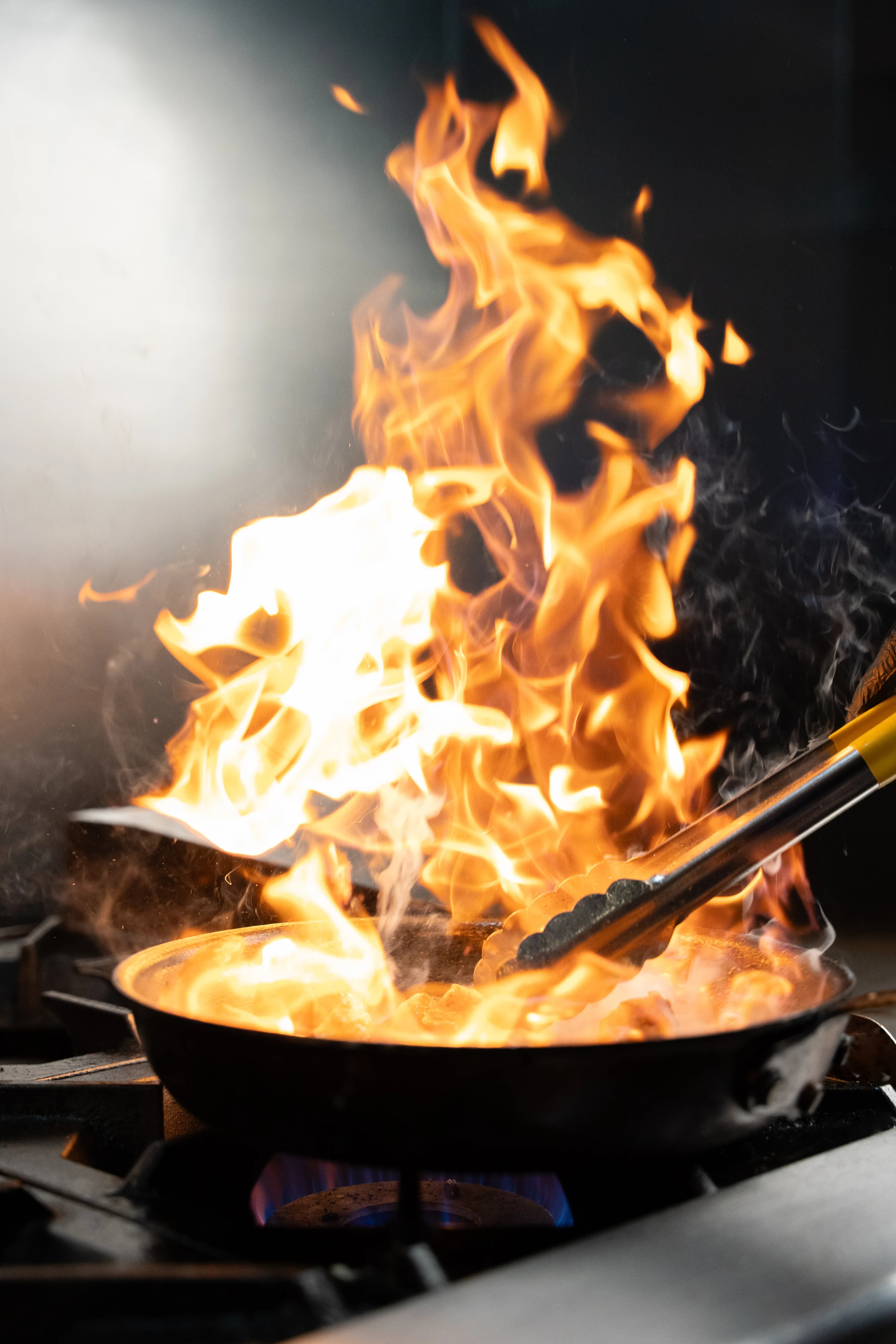 Flames leap from a sauté pan on the line at Sushi Sake.