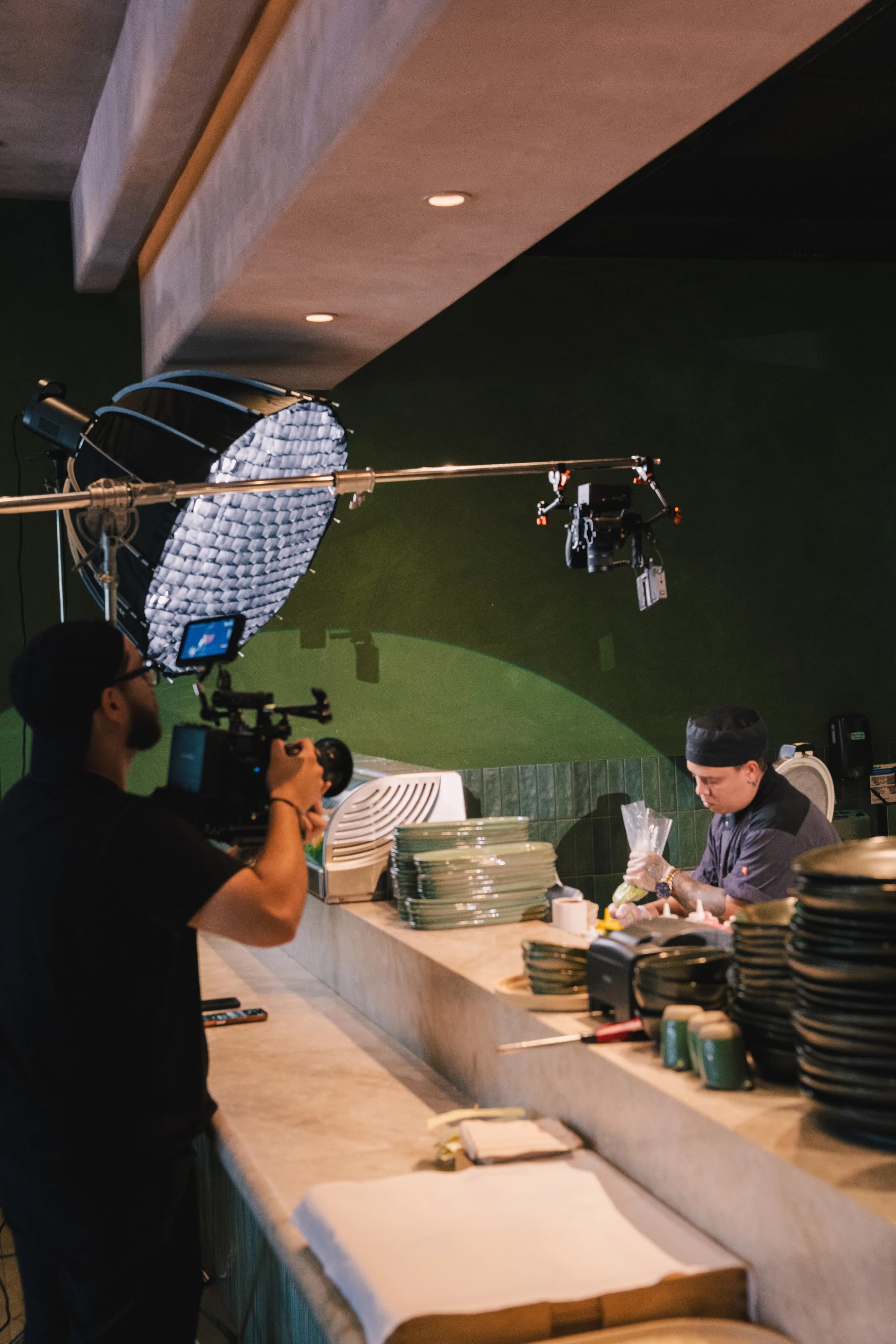 Behind the scenes — a videographer films plating at the Sushi Sake bar as chefs work.