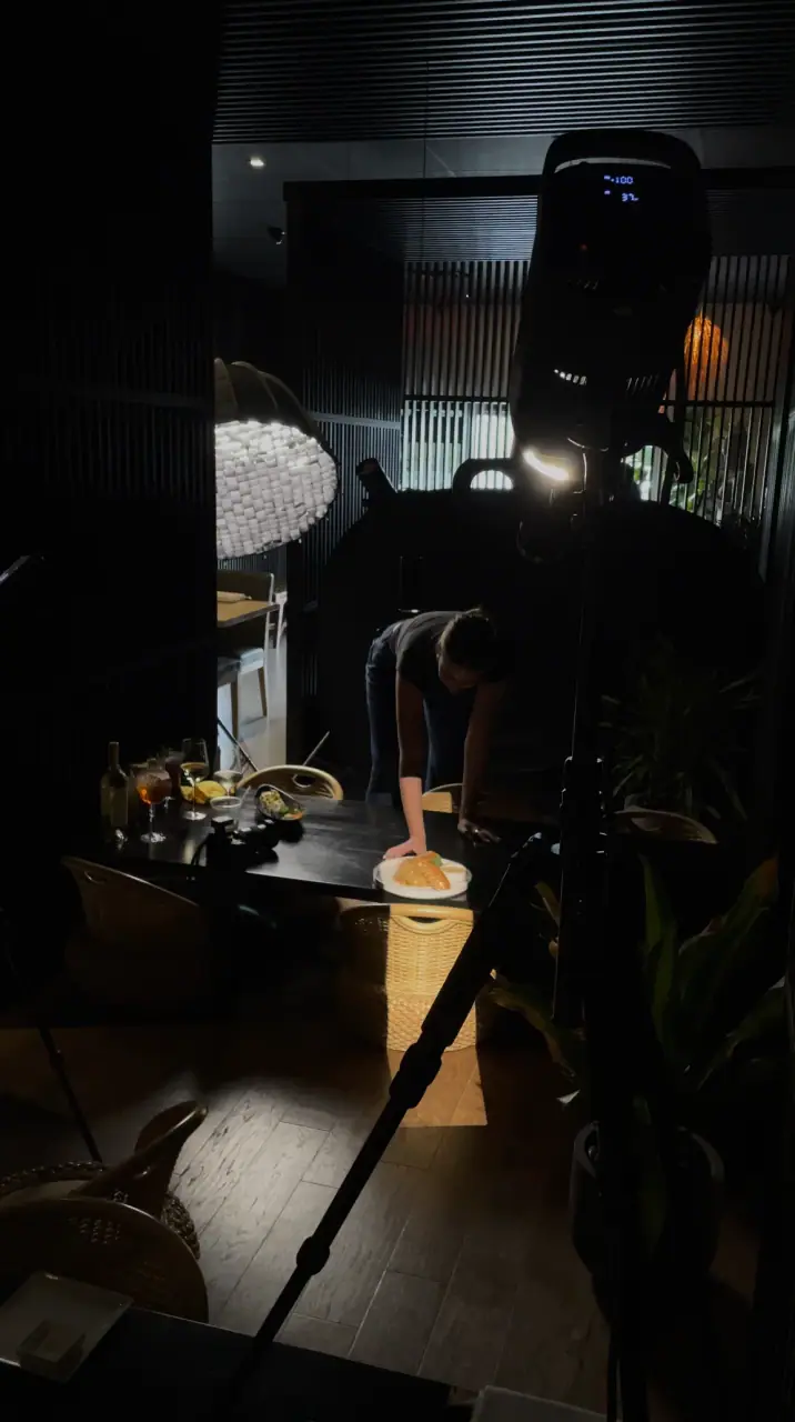 Liz styling a sushi plate under studio lights in a dark dining room.