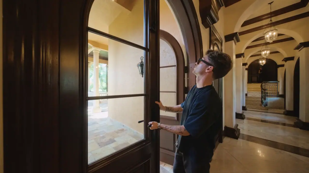 Alex opening an arched entry door in a luxury residential interior.